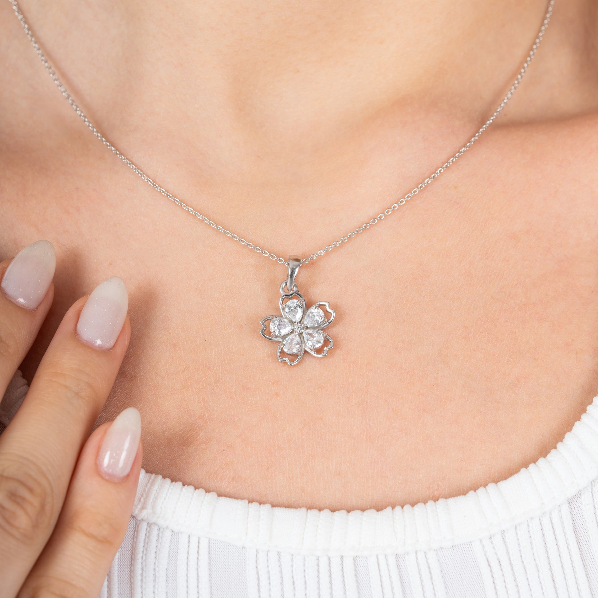Silver necklace with a floral pendant worn by a person