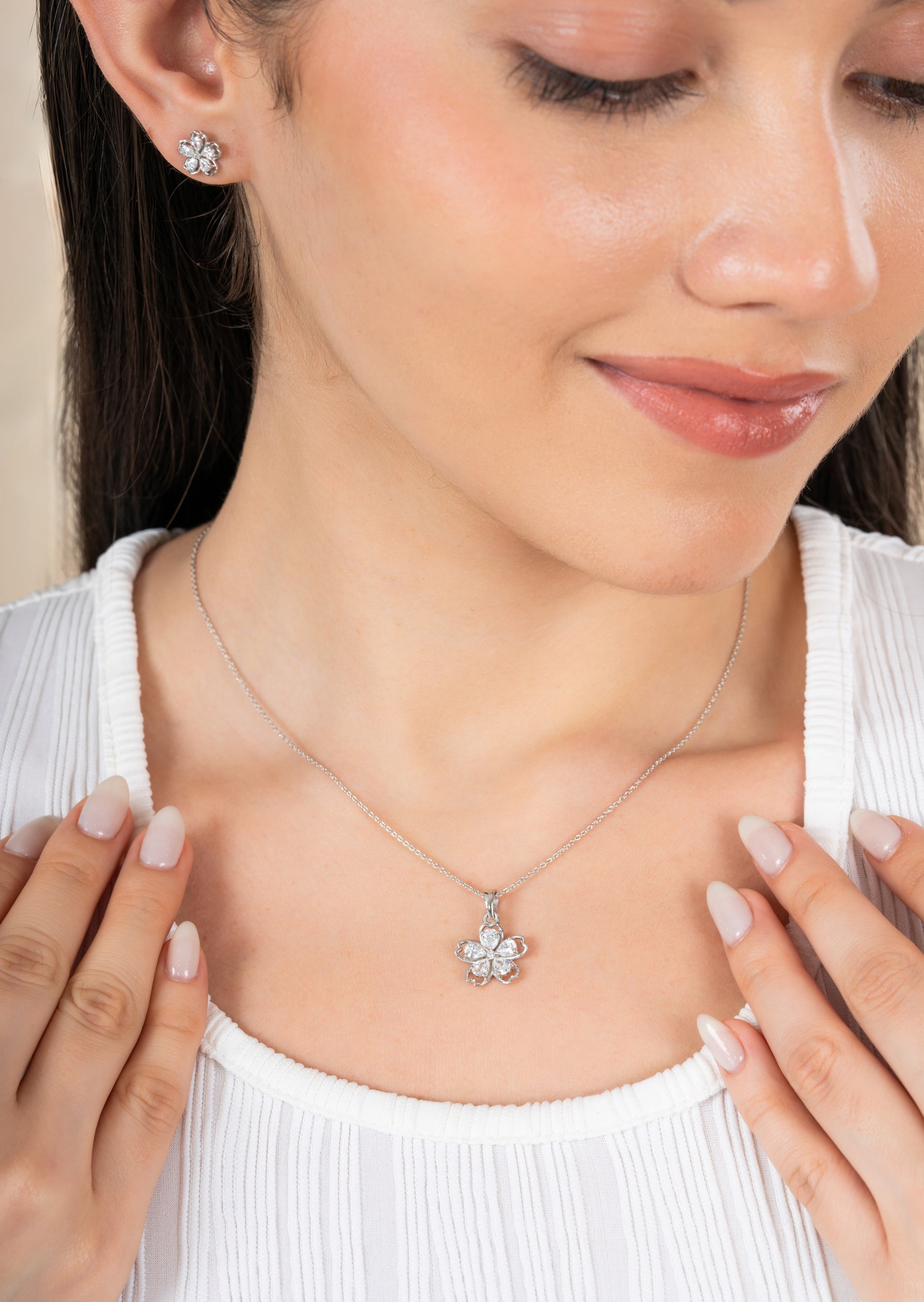 Woman wearing a silver necklace with a pendant and matching earrings.