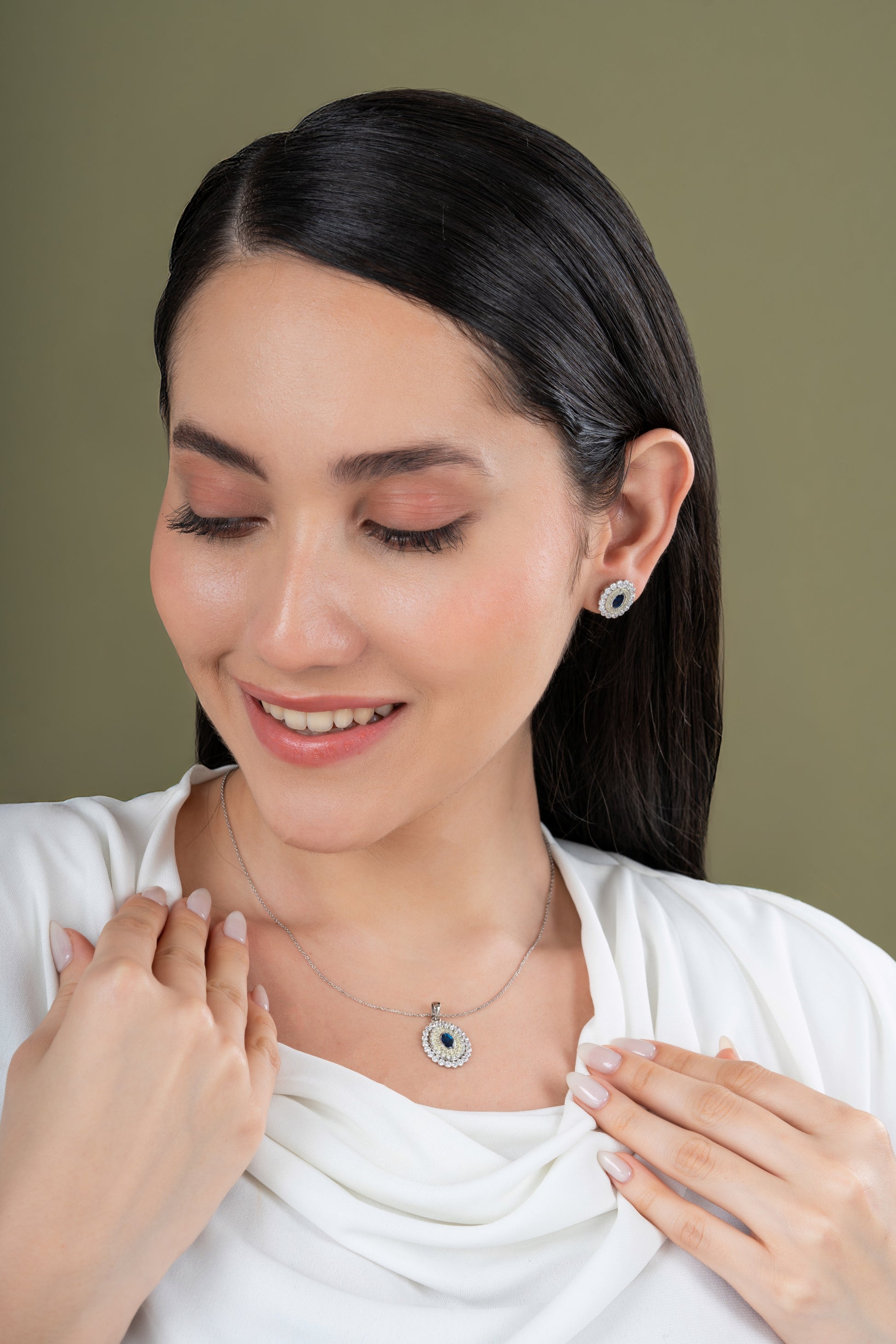Woman wearing a necklace and earrings against a green background