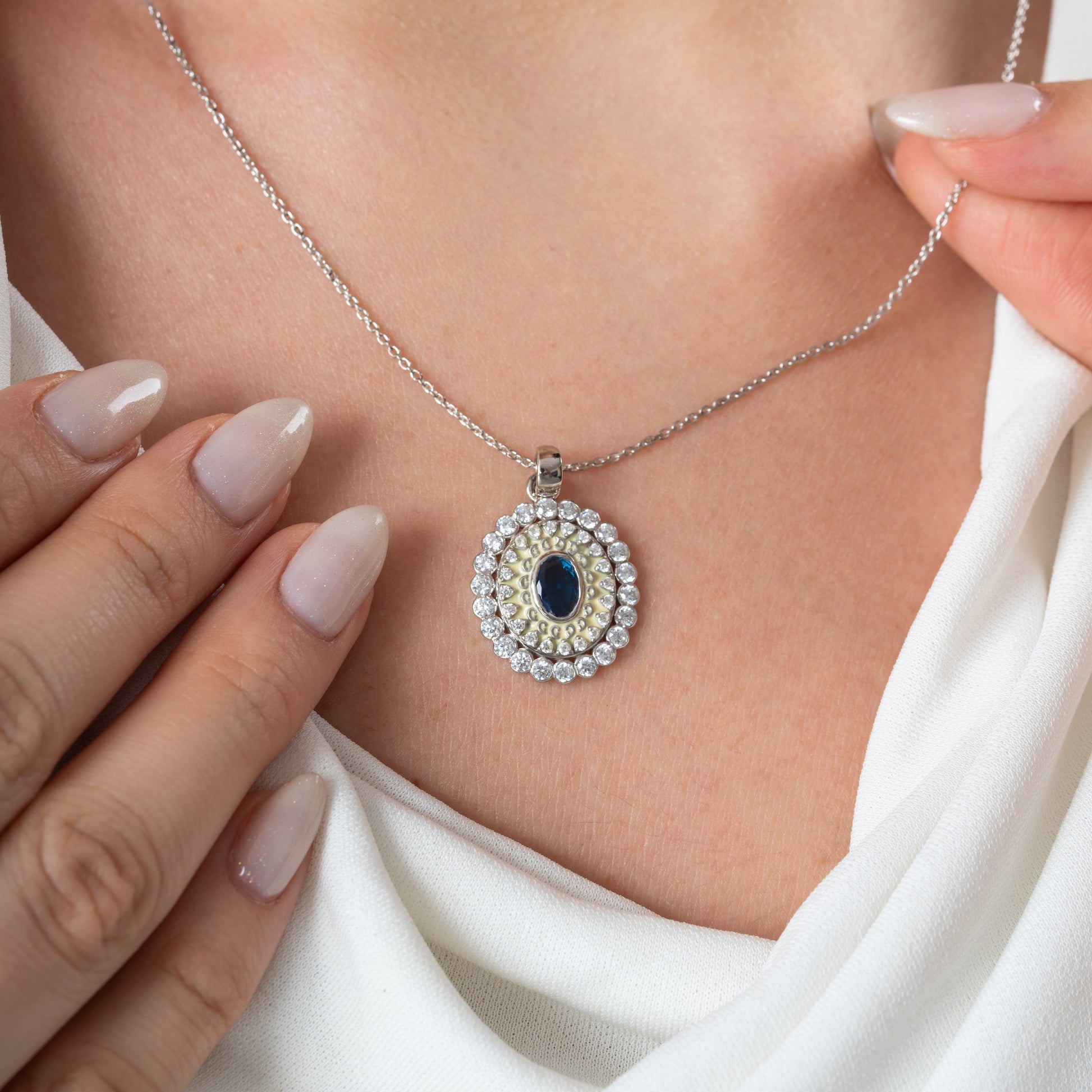Necklace with a pendant featuring a blue gemstone and pearl-like elements, worn by a person.